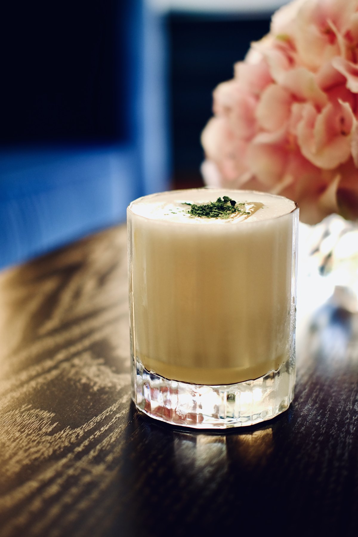 Romige cocktail naast roze bloemen